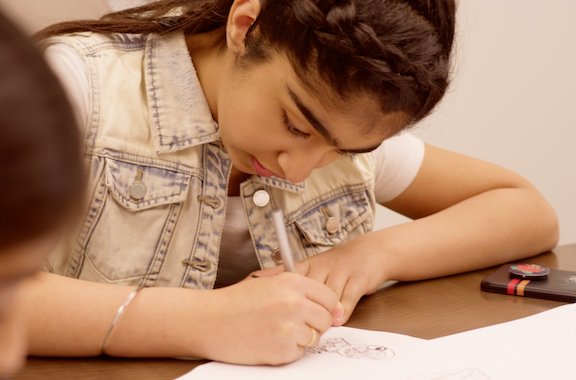 Child writing of a piece of paper for bring your child to work 2018